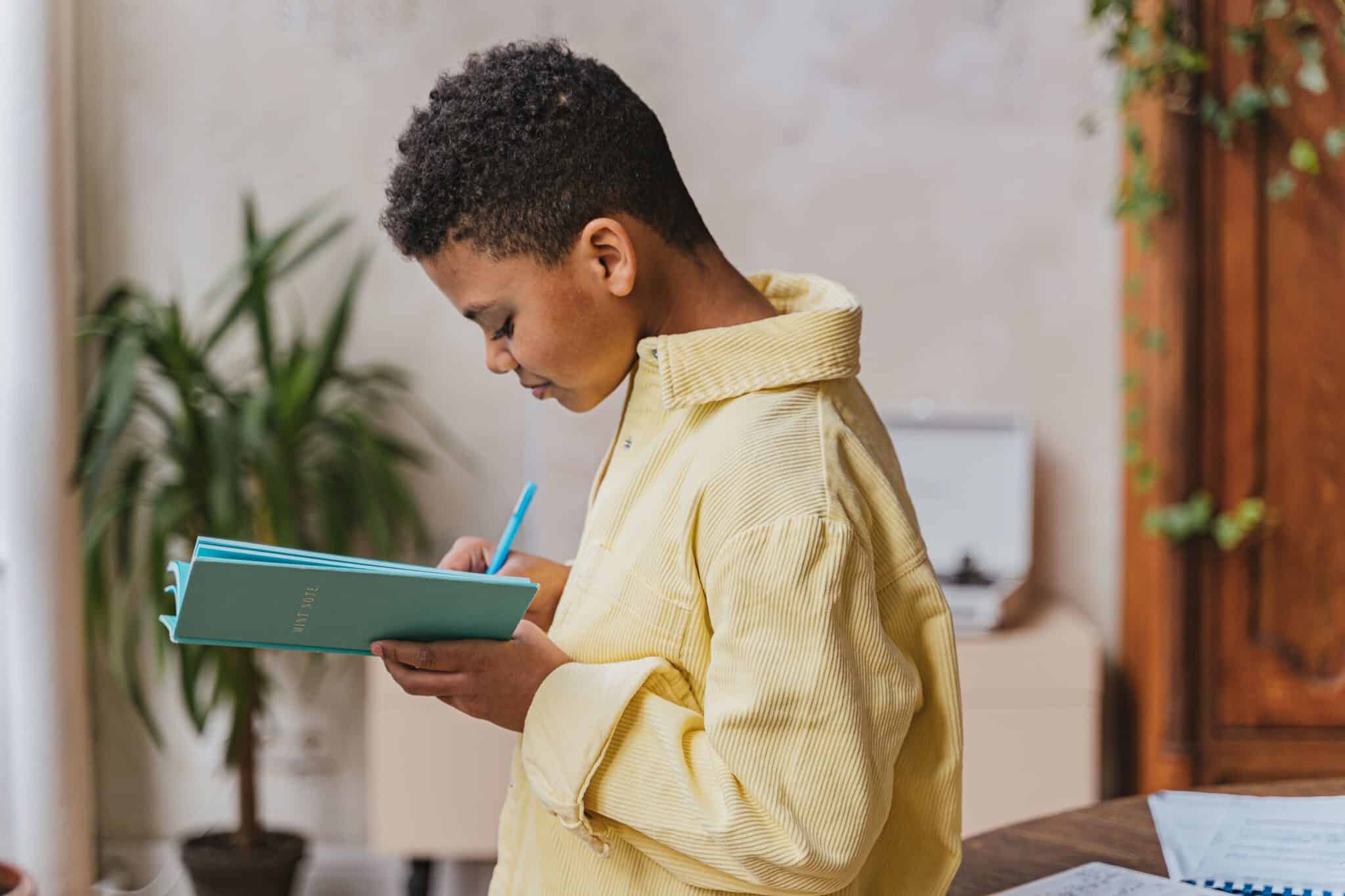 Young boy writing in a journal at home